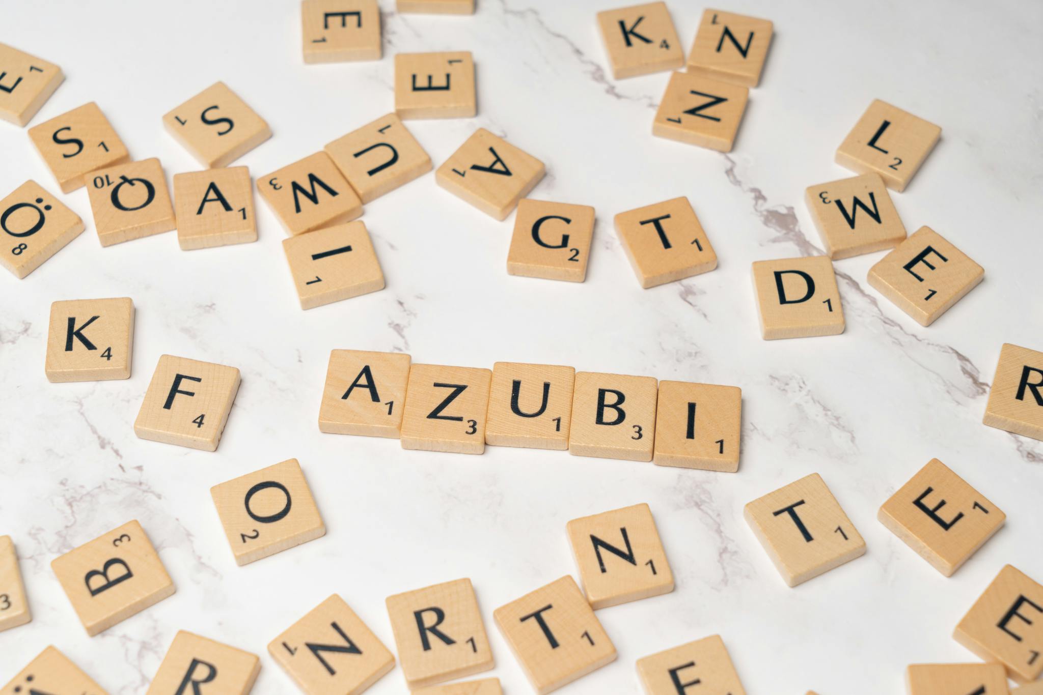 Wooden letter tiles arranged to form words on a white marble surface, perfect for education and creativity themes.